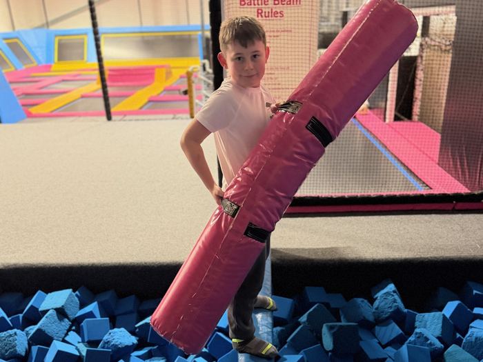 Child balancing on the Gladiator Beam over the foam pit